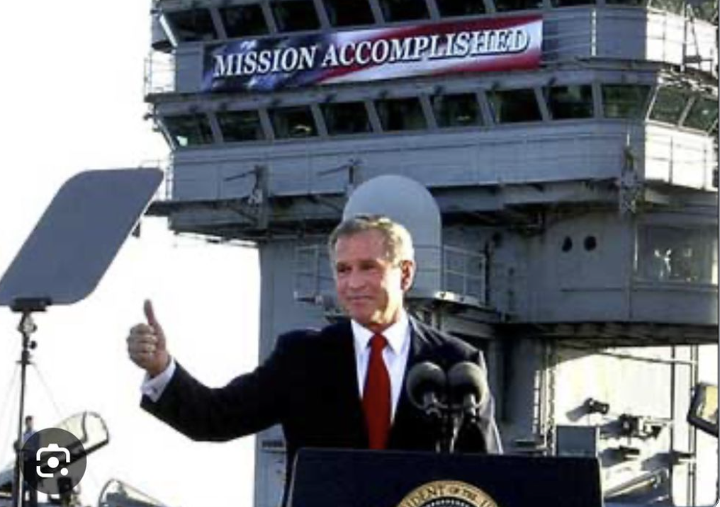 George W. Bush standing in front of a Mission Accomplished banner. 